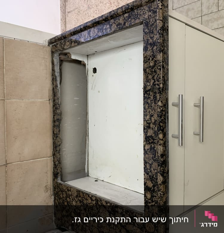 מסגרת שיש כהה סביב חלל ריק בארון מטבח